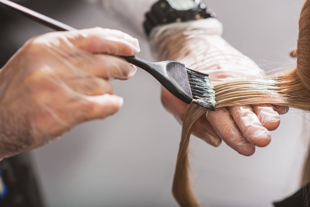 Hairstylist applying color to client's hair during signature service appointment